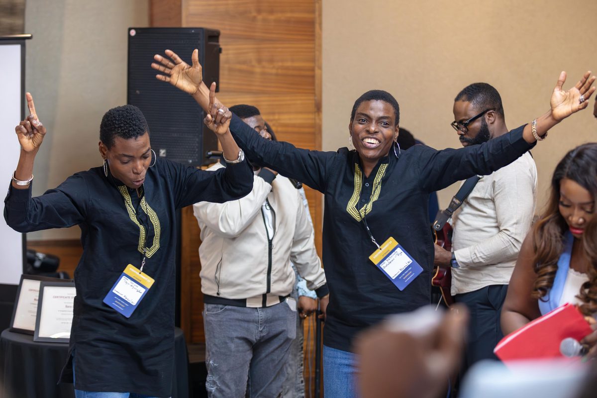 Attendees celebrating with raised arms near the stage at EventPro Connect 2.0