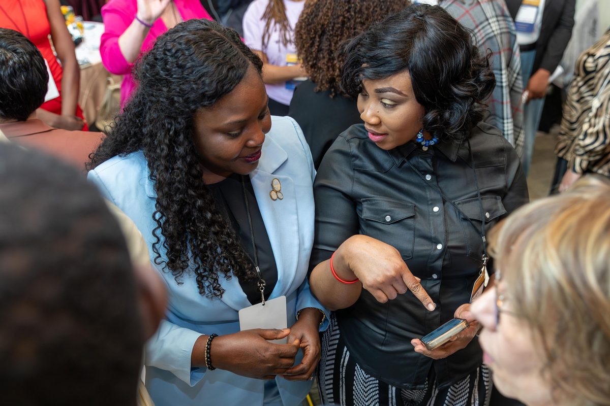 Two attendees looking at a phone together during a conversation at EventPro Connect 2.0